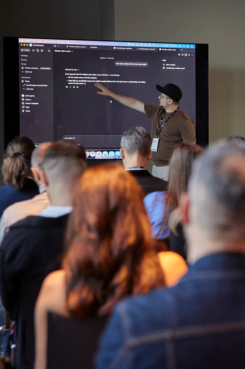 Artem at Ecom Expo 2026, pointing to a second brain answering a question on screen while the room watches.